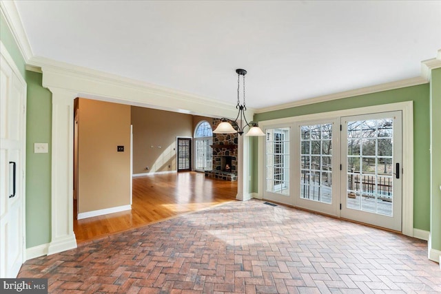 unfurnished dining area featuring crown molding, a chandelier, and ornate columns