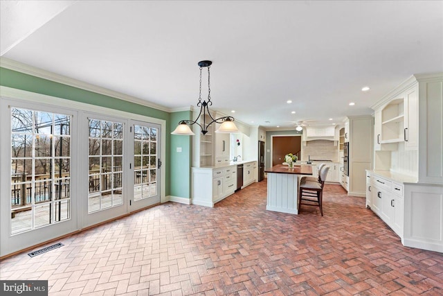 kitchen with white cabinetry, hanging light fixtures, stainless steel appliances, an island with sink, and a kitchen bar