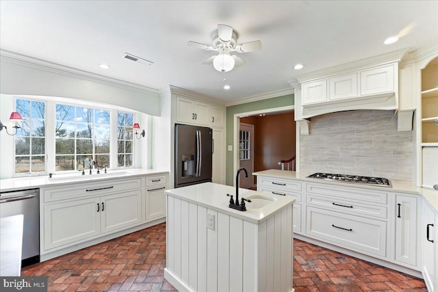 kitchen featuring sink, ornamental molding, stainless steel appliances, a kitchen island with sink, and backsplash