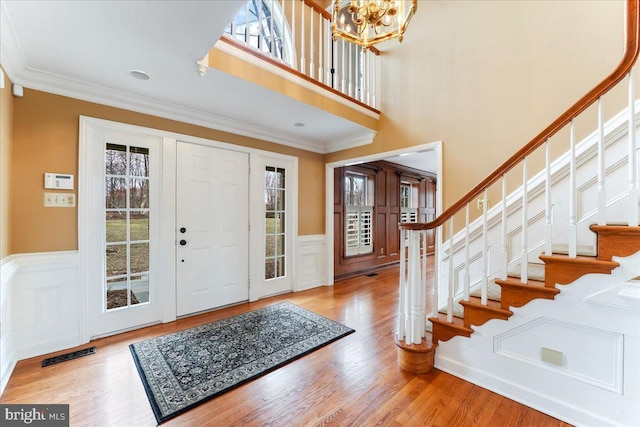 foyer with ornamental molding, a healthy amount of sunlight, and light hardwood / wood-style floors