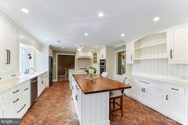 kitchen featuring a kitchen island, wooden counters, white cabinets, and appliances with stainless steel finishes