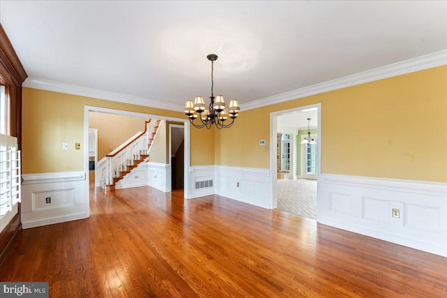 unfurnished room with an inviting chandelier, hardwood / wood-style flooring, and crown molding