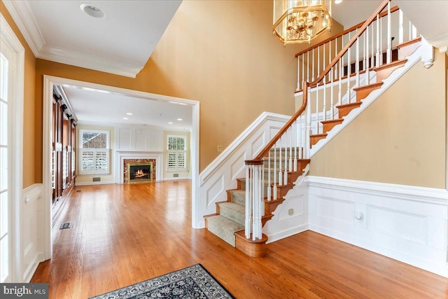 foyer featuring hardwood / wood-style floors, crown molding, and a high end fireplace