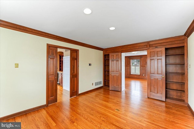 spare room with ornamental molding and light hardwood / wood-style flooring