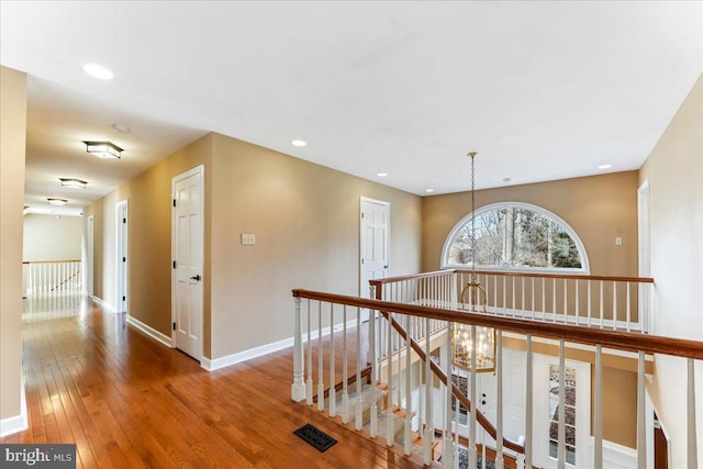 hallway with an inviting chandelier and hardwood / wood-style floors