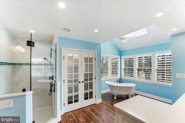 bathroom featuring ceiling fan, wood-type flooring, vaulted ceiling with skylight, and separate shower and tub