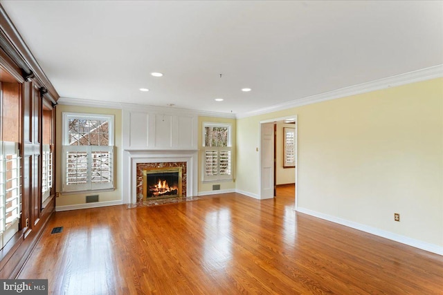 unfurnished living room featuring crown molding, a premium fireplace, and light hardwood / wood-style floors