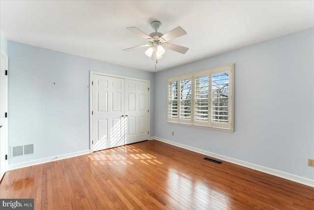 unfurnished bedroom with hardwood / wood-style floors, ceiling fan, and a closet