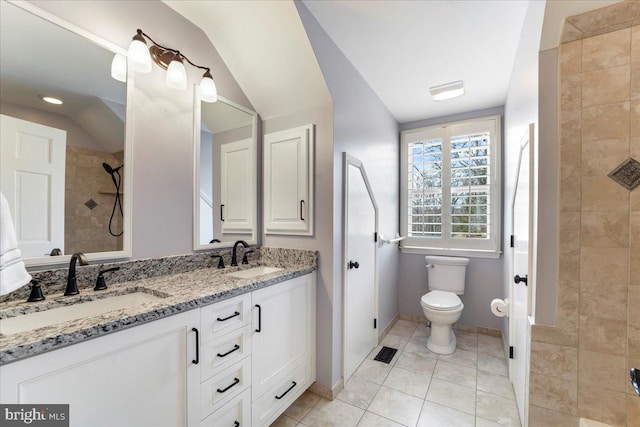 bathroom featuring tile patterned flooring, vanity, a tile shower, and toilet