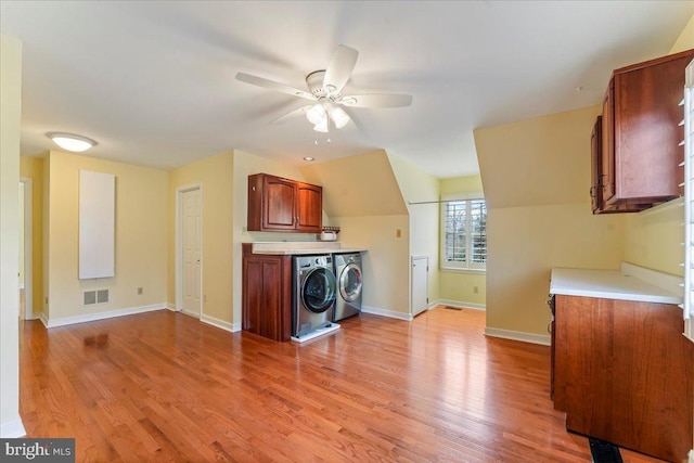 kitchen with independent washer and dryer, ceiling fan, vaulted ceiling, and light wood-type flooring