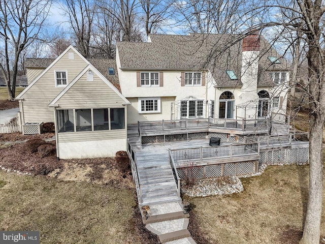 rear view of property featuring a sunroom, a yard, and a deck