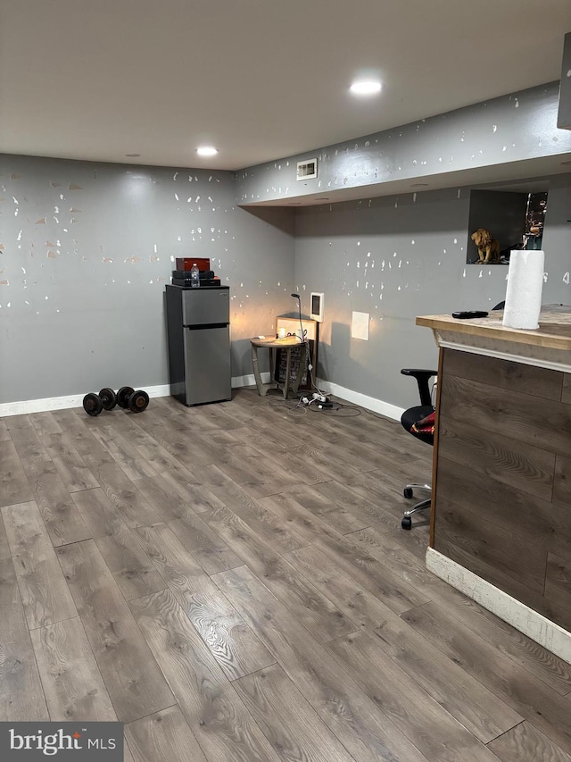 bar featuring stainless steel fridge and hardwood / wood-style floors