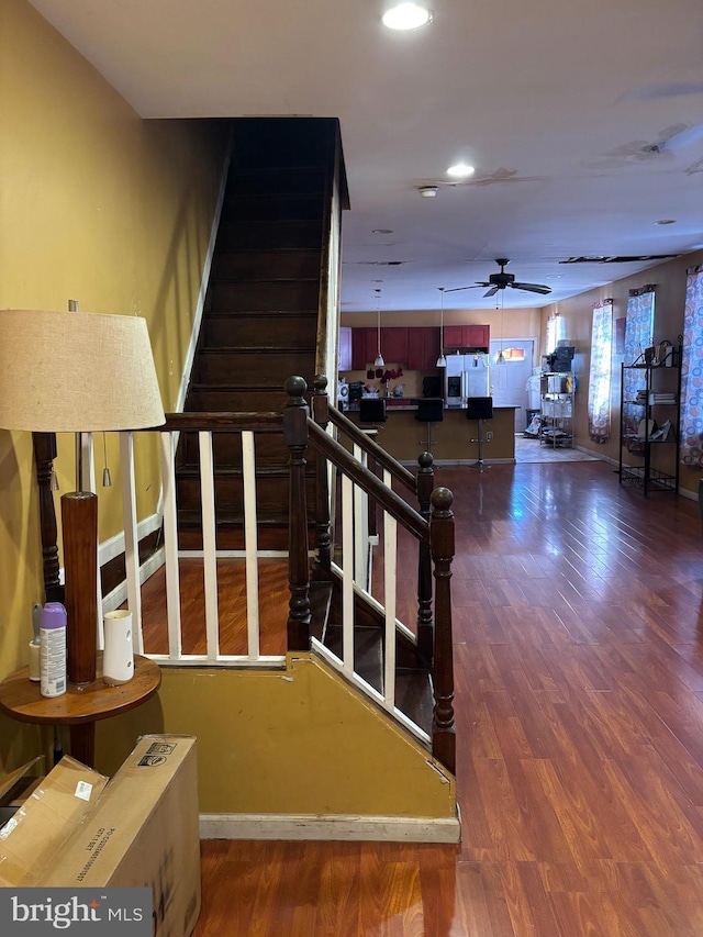 stairs featuring ceiling fan and hardwood / wood-style flooring