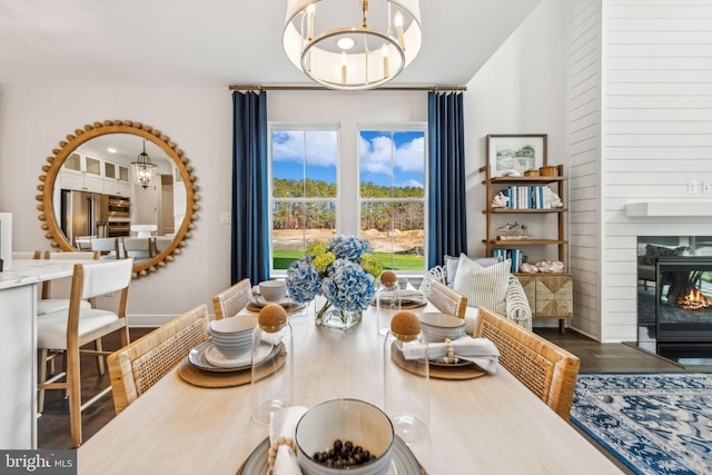 dining area with a fireplace, hardwood / wood-style floors, and a notable chandelier