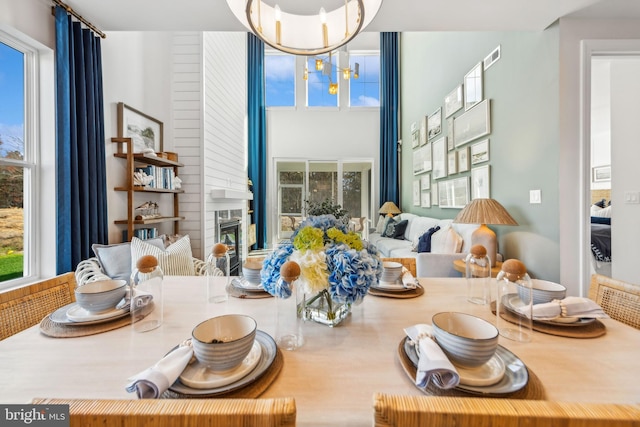 dining space with a large fireplace and an inviting chandelier