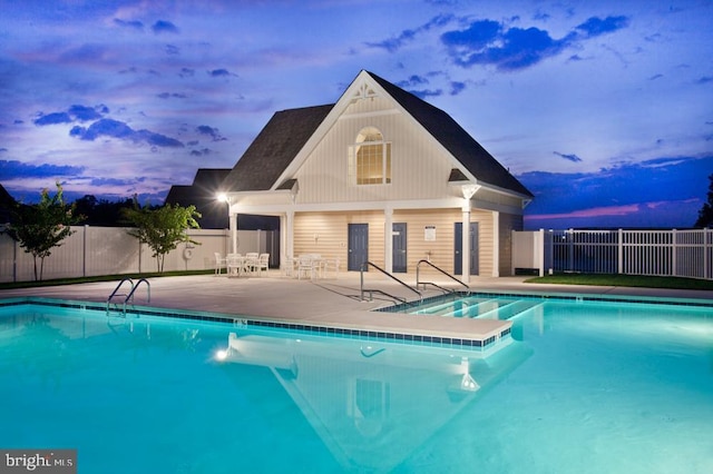 pool at dusk featuring a patio area and an outdoor structure