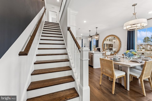 stairway with hardwood / wood-style flooring and a notable chandelier