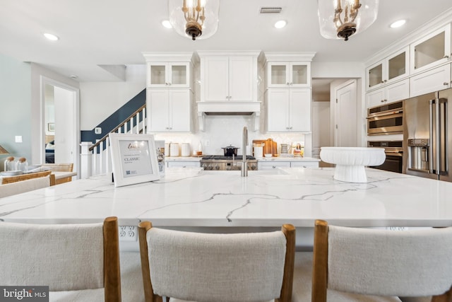 kitchen with light stone countertops, white cabinets, and hanging light fixtures