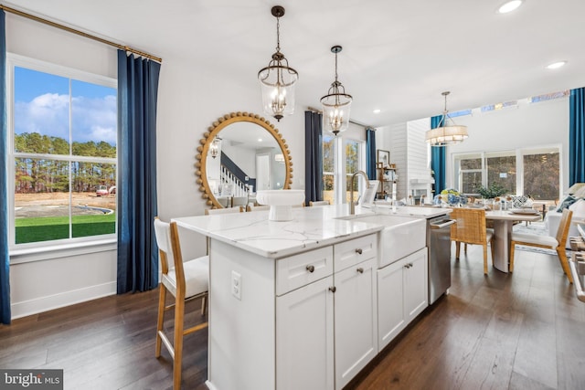 kitchen with white cabinetry, a kitchen island with sink, plenty of natural light, and light stone countertops