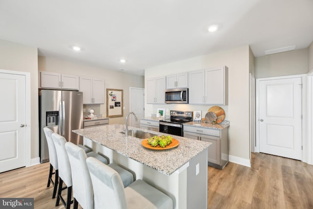 kitchen featuring a center island with sink, light hardwood / wood-style floors, sink, and stainless steel appliances