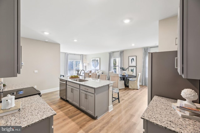 kitchen featuring a kitchen breakfast bar, sink, light wood-type flooring, an island with sink, and appliances with stainless steel finishes