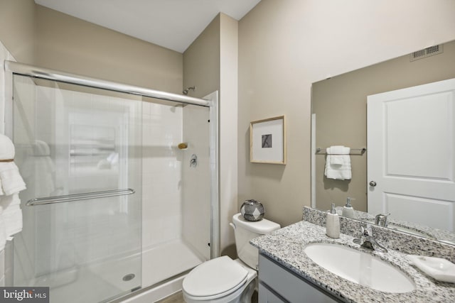 bathroom featuring a shower with door, vanity, and toilet