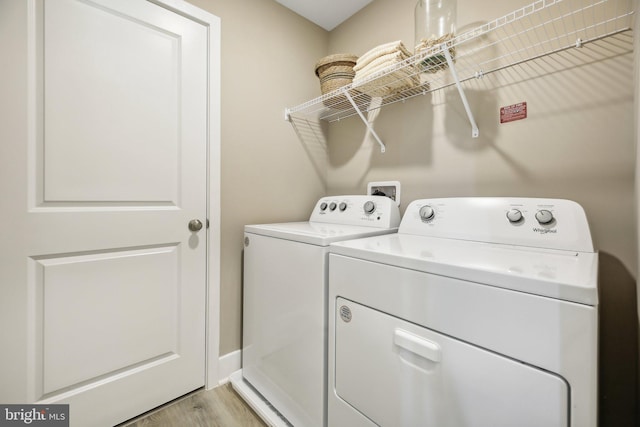 clothes washing area with separate washer and dryer and light hardwood / wood-style floors