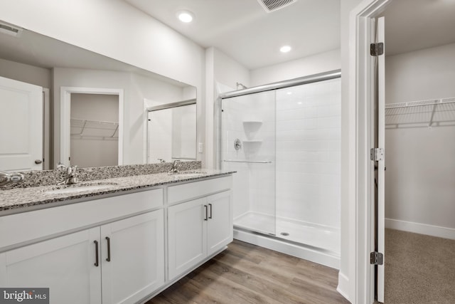 bathroom with hardwood / wood-style floors, vanity, and walk in shower