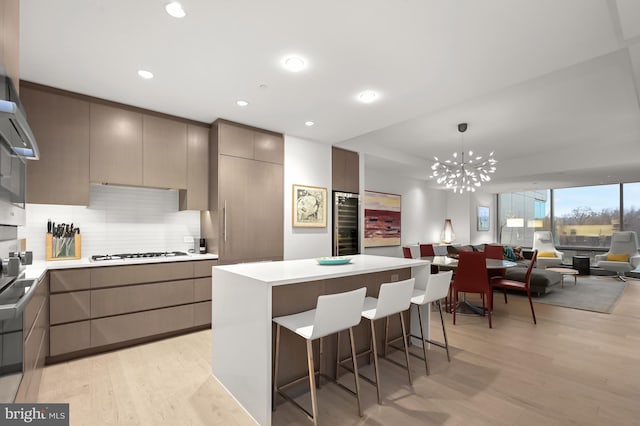 kitchen with a kitchen bar, light wood-type flooring, backsplash, and white gas stovetop