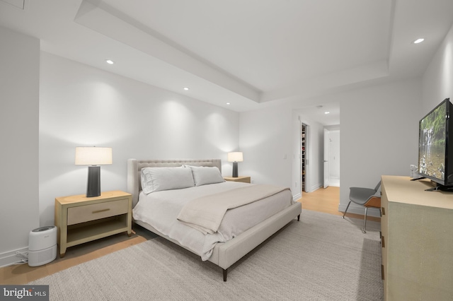 bedroom with a raised ceiling and light hardwood / wood-style flooring