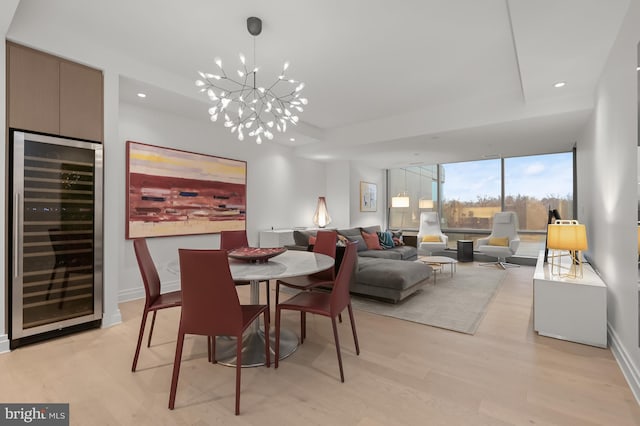 dining area featuring a chandelier, light hardwood / wood-style floors, wine cooler, and floor to ceiling windows