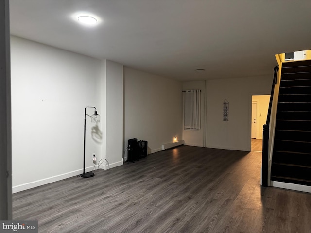 empty room featuring dark hardwood / wood-style floors and a baseboard heating unit