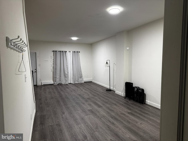 unfurnished room with baseboard heating and dark wood-type flooring