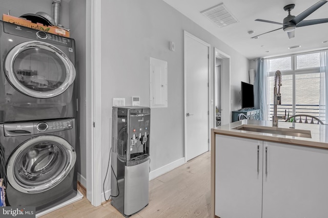 laundry room with ceiling fan, sink, stacked washer / dryer, electric panel, and light hardwood / wood-style floors