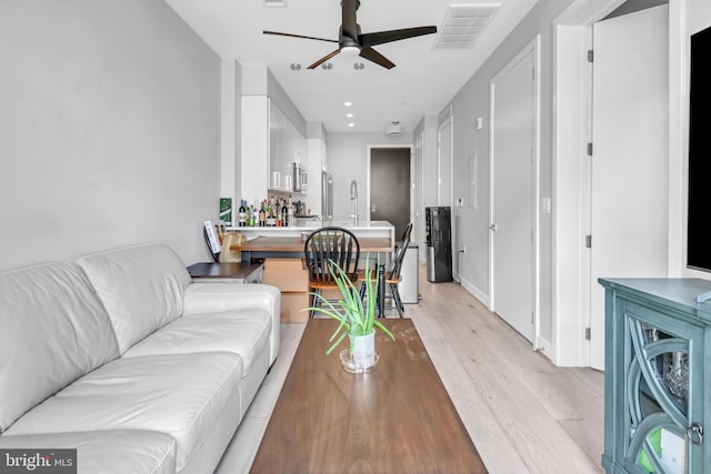 living room featuring ceiling fan and light hardwood / wood-style flooring