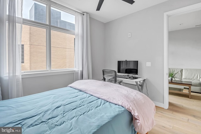 bedroom with ceiling fan, light hardwood / wood-style floors, and multiple windows