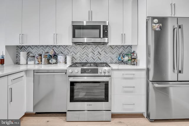 kitchen featuring white cabinetry, light stone counters, light hardwood / wood-style flooring, and stainless steel appliances