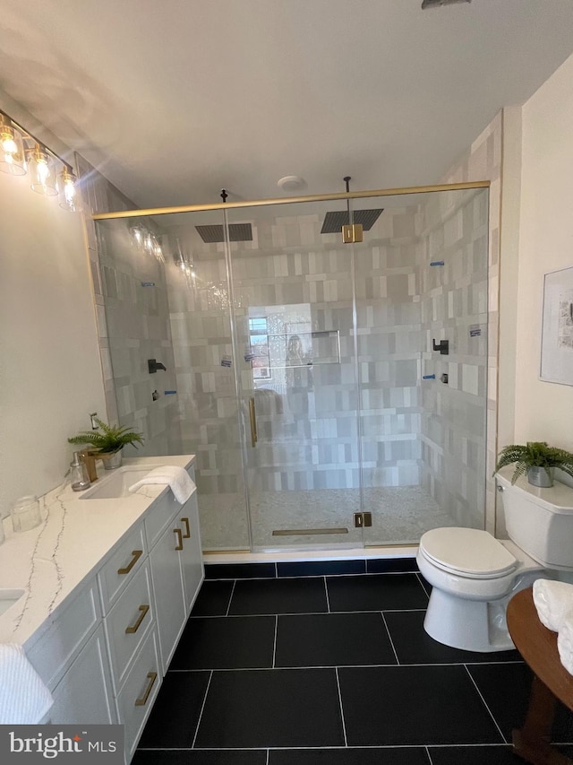 bathroom featuring tile patterned flooring, vanity, a shower with door, and toilet