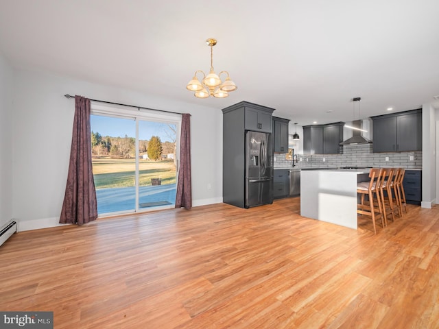 kitchen with pendant lighting, a center island, stainless steel appliances, and wall chimney exhaust hood