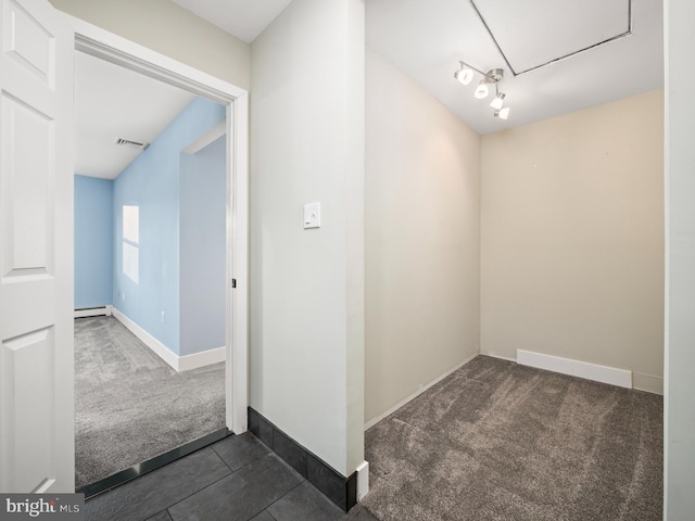 hall featuring a baseboard heating unit and dark colored carpet