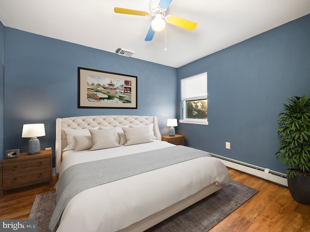 bedroom featuring hardwood / wood-style flooring, ceiling fan, and a baseboard radiator