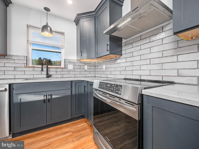 kitchen featuring sink, light hardwood / wood-style flooring, wall chimney exhaust hood, decorative backsplash, and stainless steel appliances