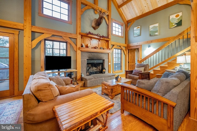 living room with wood ceiling, a wealth of natural light, light wood-type flooring, and high vaulted ceiling