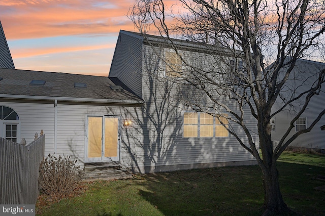 back house at dusk with a lawn