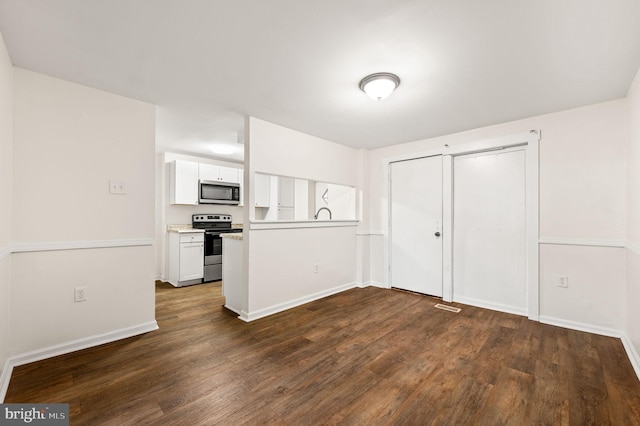 kitchen with white cabinets, appliances with stainless steel finishes, and dark wood-type flooring