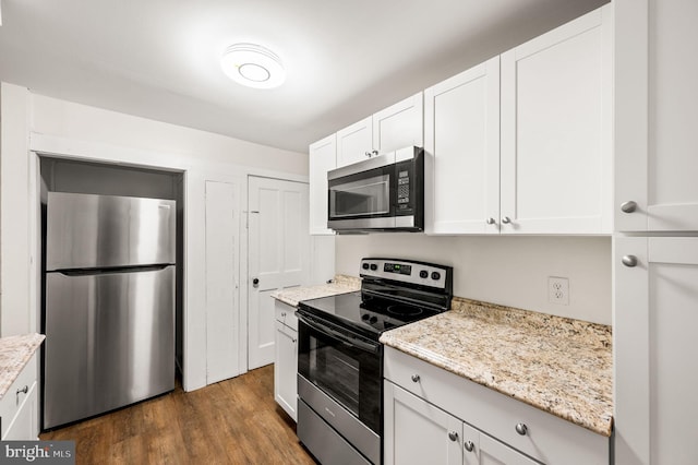 kitchen with light stone countertops, white cabinetry, stainless steel appliances, and dark wood-type flooring