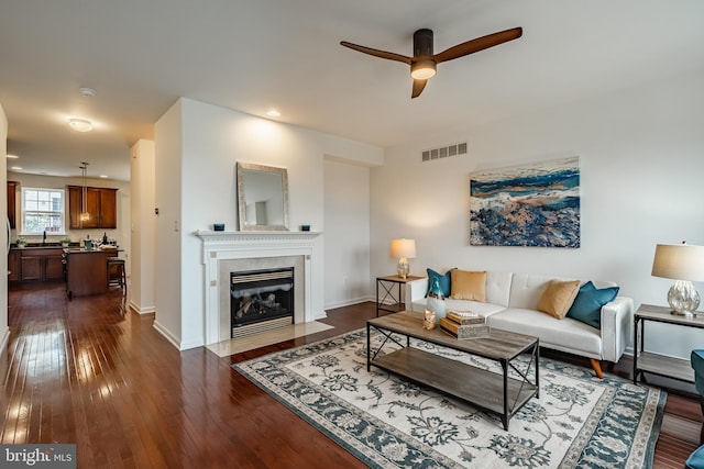 living room with ceiling fan, sink, and dark wood-type flooring