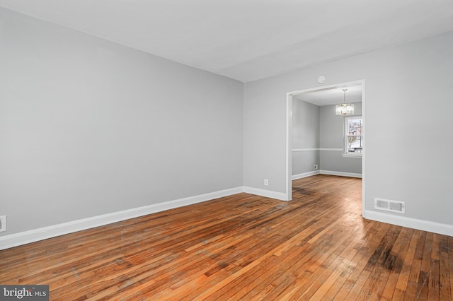 spare room with wood-type flooring and a notable chandelier