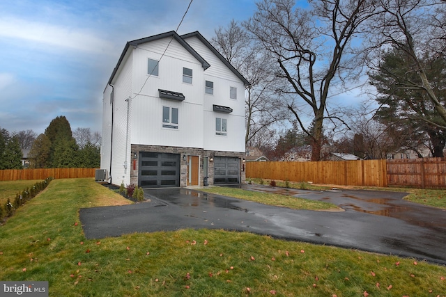 back of house featuring a yard, a garage, and central air condition unit