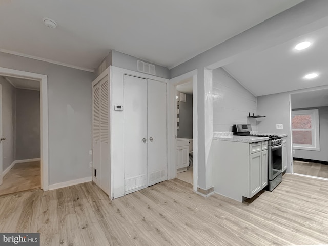 kitchen with stainless steel gas range oven, crown molding, vaulted ceiling, white cabinets, and light wood-type flooring